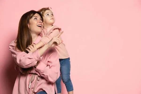 Sueños. Retrato de mujer joven y niña, madre e hija aisladas sobre fondo de estudio rosa. Celebración del Día de las Madres. Concepto de familia, infancia, maternidad — Foto de Stock