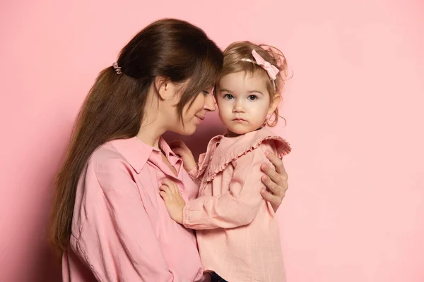 Potret wanita muda dan gadis kecil, ibu dan putri terisolasi di latar belakang studio merah muda. Ibu-ibu perayaan Hari. Konsep keluarga, masa kecil, keibuan — Stok Foto