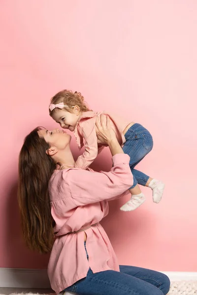 Porträtt av ung kvinna och liten flicka, mor och dotter isolerad på rosa studio bakgrund. Mors dag firande. Begreppet familj, barndom, moderskap — Stockfoto