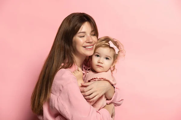 Huggins. Portrait de jeune femme et petite fille, mère et fille isolées sur fond de studio rose. Fête des Mères. Concept de famille, enfance, maternité — Photo