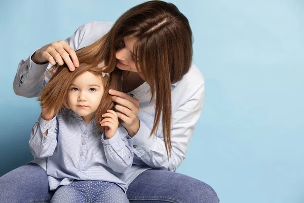 Estúdio tiro de mulher feliz bonita e criança pequena, mãe e filha isolada no fundo azul. Celebração do Dia das Mães. Conceito de família, infância — Fotografia de Stock