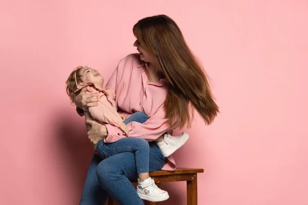 Szczęśliwa kobieta i mała dziewczynka, opiekuńcza matka i córka odizolowane na różowym tle studio. Święto Matki. Pojęcie rodziny, dzieciństwa, macierzyństwa — Zdjęcie stockowe