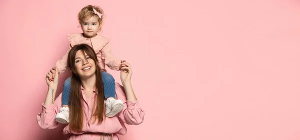 Flyer avec femme heureuse et petite fille, mère attentionnée et fille isolée sur fond de studio rose. Fête des Mères. Concept de famille, enfance, maternité — Photo