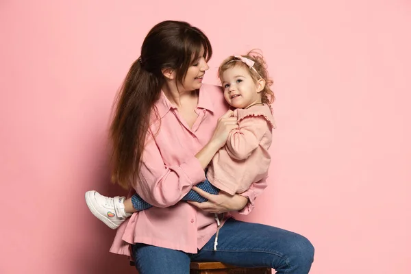 Femme heureuse et petite fille, mère attentionnée et fille isolée sur fond de studio rose. Fête des Mères. Concept de famille, enfance, maternité — Photo