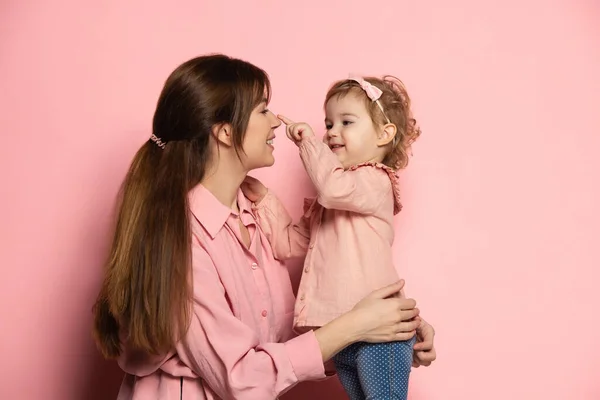 Happy woman and little girl, caring mother and daughter isolated on pink studio background. Mothers Day celebration. Concept of family, childhood, motherhood — Stock Photo, Image