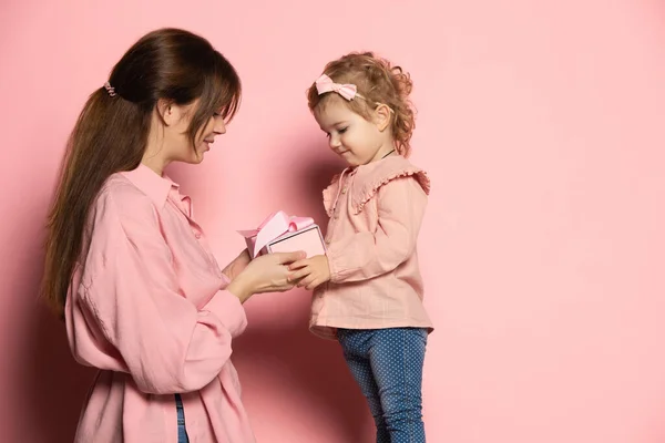 Délicieuse jeune femme et tout-petit, mère et fille attentionnées isolées sur fond de studio rose. Fête des Mères. Concept de famille, enfance, maternité — Photo