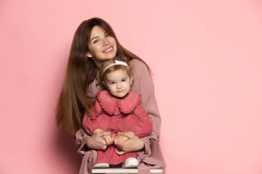 Sarılalım. Mutlu genç bir kadın ve yeni yürümeye başlayan bir çocuk, özenli bir anne ve kız pembe stüdyo geçmişinde izole edilmiş. Anneler Günü kutlaması. Aile kavramı, çocukluk, annelik.