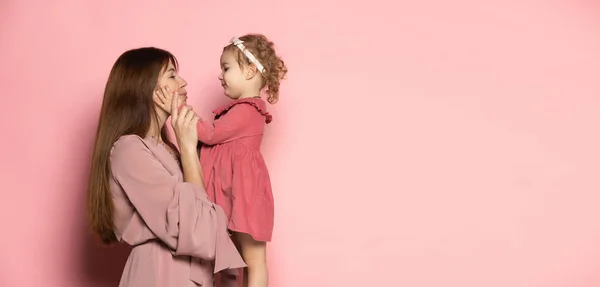 若い女性と幼児、ピンクのスタジオの背景に隔離された思いやりのある母親と娘。母の日のお祝い。家族、子供時代、母親という概念 — ストック写真