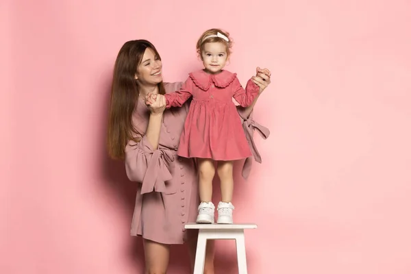 Délicieuse jeune femme et tout-petit, mère et fille attentionnées isolées sur fond de studio rose. Fête des Mères. Concept de famille, enfance, maternité — Photo