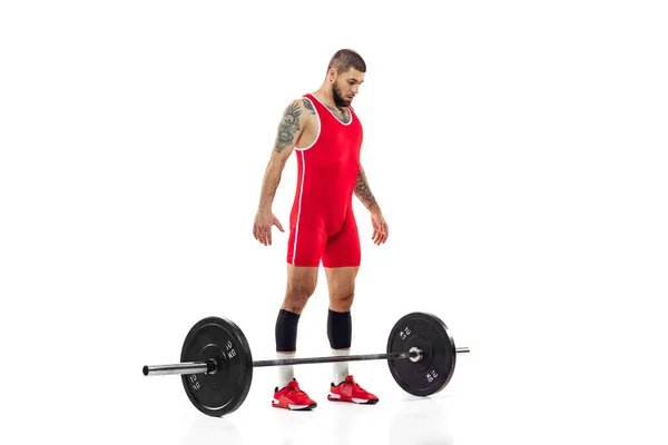 Retrato completo del hombre en ropa deportiva roja haciendo ejercicio con un peso aislado sobre fondo blanco. Deporte, levantamiento de pesas, poder, concepto de logros —  Fotos de Stock