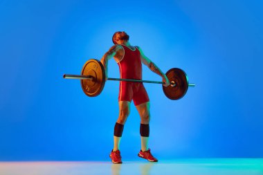 Kırmızı spor giyim giymiş, halterle egzersiz yapan genç bir adamın neon renkli mavi arka plan görüntüsü. Spor, halter, güç, başarı konsepti