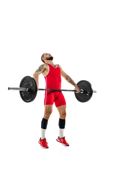 Ritratto a figura intera dell'uomo in abbigliamento sportivo rosso che si esercita con un peso isolato su sfondo bianco. Sport, sollevamento pesi, potenza, concetto di risultati — Foto Stock