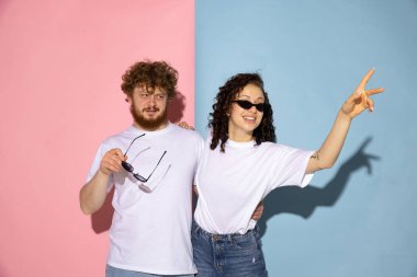 Mavi ve pembe renkli arka planda izole edilmiş beyaz tişörtlü genç ve heyecanlı adamın yarım boy portresi. İnsan duyguları kavramı