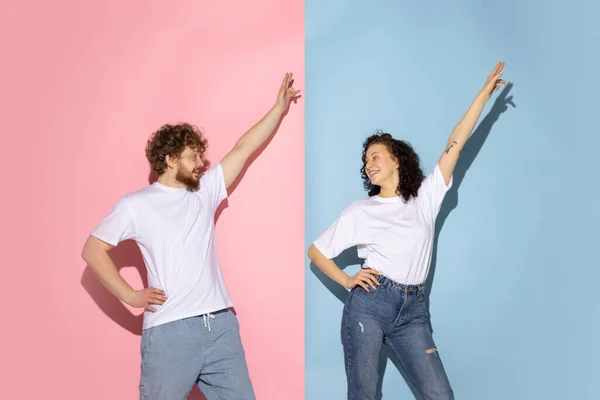 Emotioneel koppel jong grappig en gelukkig man en meisje dansen hip-hop in studio op blauw en roze trendy kleur achtergrond. — Stockfoto