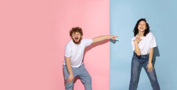 Couple excité de jeunes homme et fille drôle et heureux riant studio sur fond bleu et rose couleur tendance. — Photo