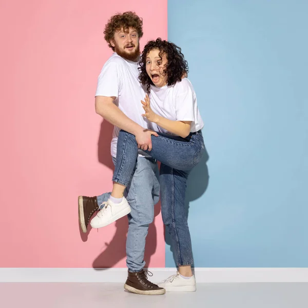 Portret van jonge emotionele man en meisje poseren geïsoleerd op blauwe en roze trendy kleur achtergrond. Menselijke emoties concept — Stockfoto