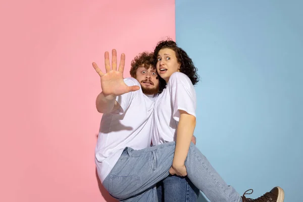 Portrait of young emotive man and girl posing isolated on blue and pink trendy color background. Human emotions concept — Stock Photo, Image