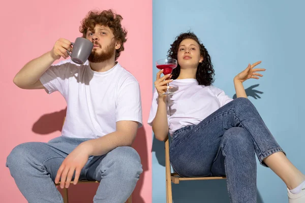 Married couple, young emotive man and girl tasting drinks isolated on blue and pink trendy color background. Human emotions, care, relationships concept — Stock Photo, Image