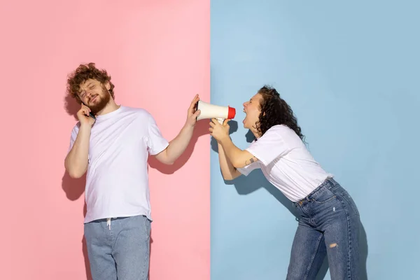 Getrouwd stel, jonge emotionele man en meisje geïsoleerd op blauwe en roze trendy kleur achtergrond. Menselijke emoties, zorg, relaties concept — Stockfoto