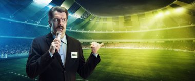 Komik adam, profesyonel spor spikeri çevrimiçi televizyon yayınına sahip, futbol maçı stadyumun arka planında izole edilmiş.