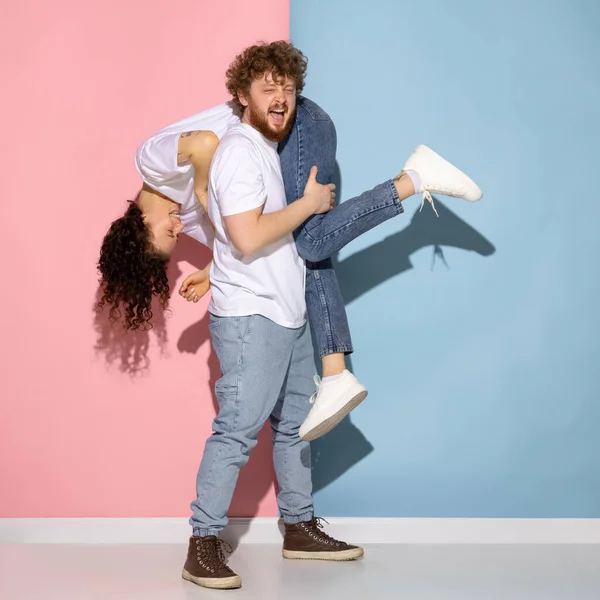 Emotioneel paar jong grappig en gelukkig man en meisje met plezier studio op blauw en roze trendy kleur achtergrond. — Stockfoto