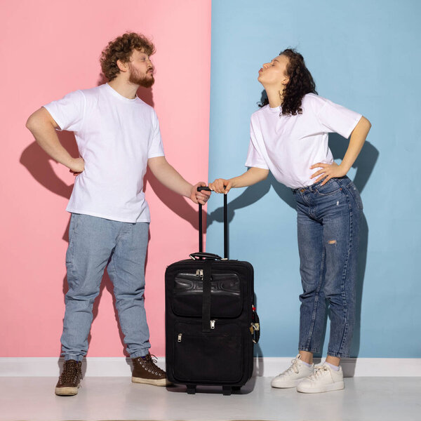 Married couple, young emotive man and girl goint on vacation isolated on blue and pink trendy color background. Relationships, travel, holiday concept