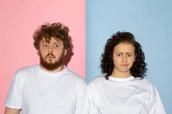 Half length portrait of young emotive man and girl making faces isolated on blue and pink trendy color background. Human emotions concept — Stock Photo, Image