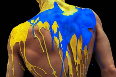 Kavramsal görüntü. Siyah zemin üzerinde izole edilmiş Ukrayna bayrağının mavi ve sarı renkleriyle kaplı büyük, güçlü erkek sırt.