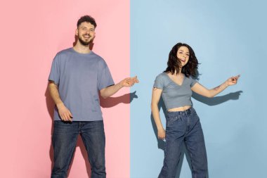 Heyecanlı genç bir çift, eğlenceli ve mutlu erkek ve kız hip-hop yapıyor, mavi ve pembe renkli arka planda izole edilmiş şekilde eğleniyorlar. Duygular konsepti
