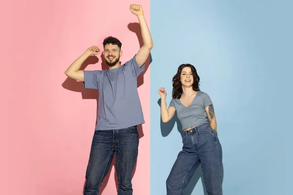 Jong opgewonden paar grappige en vrolijke man en meisje dansen hip-hop, plezier geïsoleerd op blauw en roze trendy kleur achtergrond. Emoties concept — Stockfoto