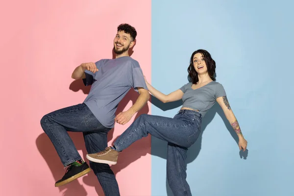 Jovem casal animado de homem engraçado e feliz e menina dançando hip-hop, se divertindo isolado no fundo azul e rosa da moda cor. Conceito de emoções — Fotografia de Stock