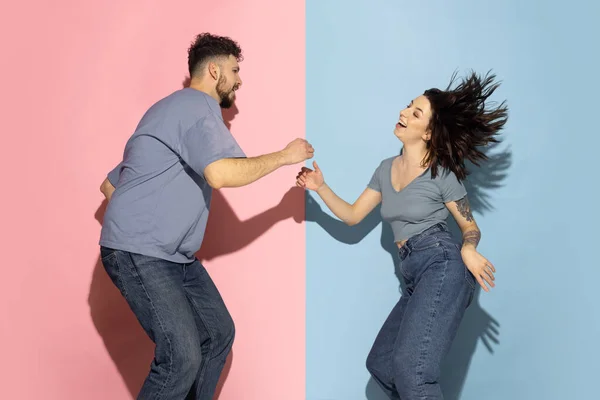 Jong opgewonden paar grappige en vrolijke man en meisje dansen hip-hop, plezier geïsoleerd op blauw en roze trendy kleur achtergrond. Emoties concept — Stockfoto