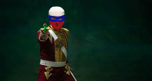 Портрет людини в костюмі Миколи II, одягнений в червоний, білий і синій балаклаву, ізольований на темно-зеленому тлі. Стиль ретро, порівняння концепції епох. Історія — стокове фото