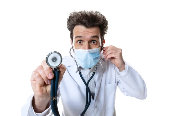 Muž mladý lékař se stetoskopem a obličejovou maskou na bílém pozadí studia. Koncepce zdravotnictví a medicíny, válka, pomoc, léčba — Stock fotografie