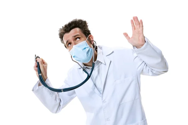 Muž mladý lékař se stetoskopem a obličejovou maskou na bílém pozadí studia. Vypadá to smutně, vážně. Koncepce zdravotnictví a medicíny, válka, pomoc, léčba — Stock fotografie