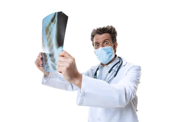 Hombre joven médico con estetoscopio y mascarilla en fondo blanco estudio. Parece triste, serio. Concepto de salud y medicina, guerra, ayuda, tratamiento — Foto de Stock