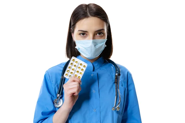 Porträtt av ung kvinna, läkare, terapeutisk eller medicinsk rådgivare bär ansiktsmask och blå uniform isolerad på vit bakgrund. — Stockfoto
