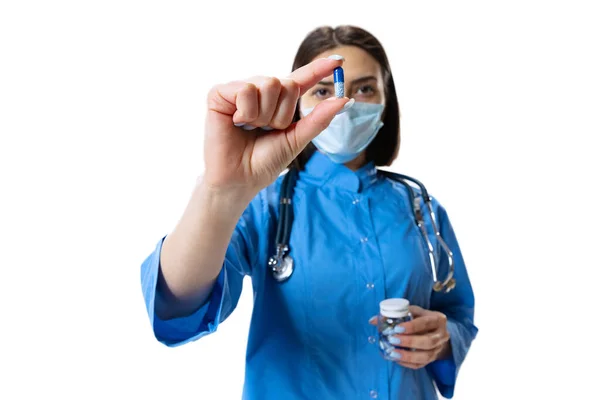 Närbild. Porträtt av ung kvinna, läkare, terapeutisk eller medicinsk rådgivare bär ansiktsmask och blå uniform isolerad på vit bakgrund. — Stockfoto