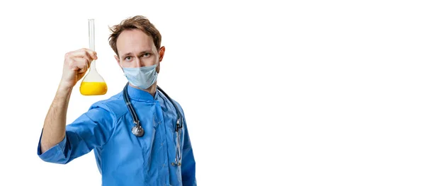 Joven químico, doctor vistiendo uniforme azul, mascarilla facial y guantes lleva a cabo investigación química aislada sobre fondo blanco. Concepto de salud, productos farmacéuticos, medicina. — Foto de Stock