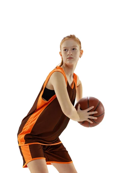 Porträtt av ung aktiv flicka, tonåring, basketspelare i brun uniform utbildning isolerad över vit studio bakgrund — Stockfoto