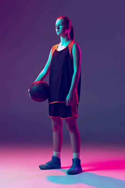 Retrato de niña, jugador de baloncesto adolescente en uniforme posando aislado sobre degradado rosa púrpura fondo en neón — Foto de Stock