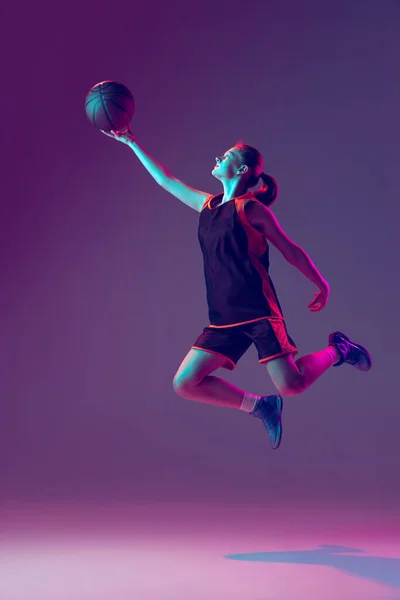 Ritratto di giovane ragazza attiva, allenamento professionale del giocatore di basket isolato su sfondo rosa porpora sfumato al neon — Foto Stock