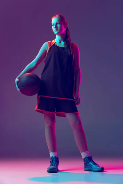 Retrato de jugador de baloncesto adolescente en uniforme posando aislado sobre degradado rosa púrpura fondo en neo — Foto de Stock