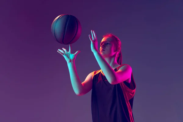 Retrato de chica joven, entrenamiento de jugador de baloncesto, bola giratoria en el dedo aislado sobre fondo rosa púrpura degradado en neón —  Fotos de Stock