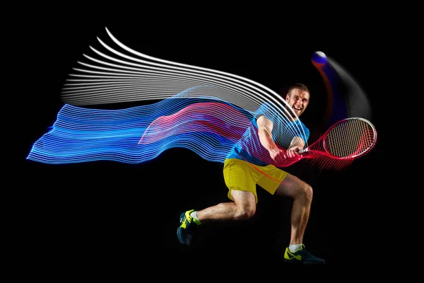 Dynamiskt porträtt av kaukasisk man spelar tennis isolerad på mörk bakgrund med blandade färgade stipes. Begreppet idrott, hobby, utmaningar, fred, politik — Stockfoto