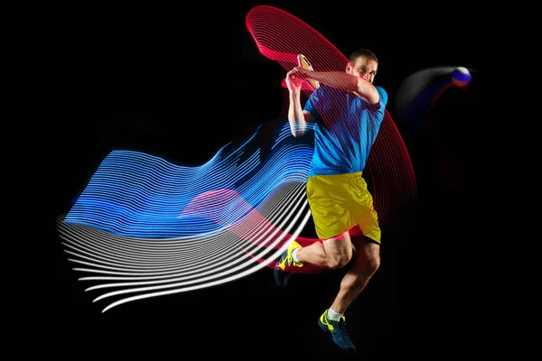 Portrait de jeune homme jouant au tennis isolé sur fond sombre avec des stipes de couleur mélangée. Concept de sport, passe-temps, défis, paix, politique — Photo