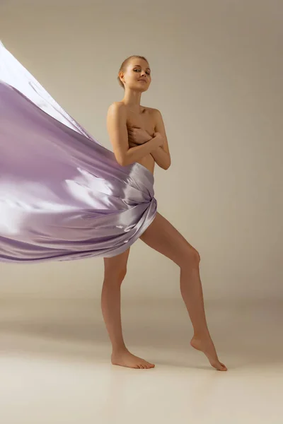 Retrato de mujer hermosa cubierta con fabrik de seda púrpura claro aislado sobre fondo de estudio beige — Foto de Stock