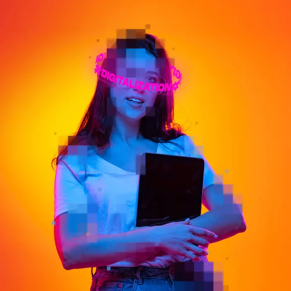 Contemporary artwork. Ypung girl with pixel head and neon lettering around holding tablet isolated over orange background in neon — Stock Photo, Image