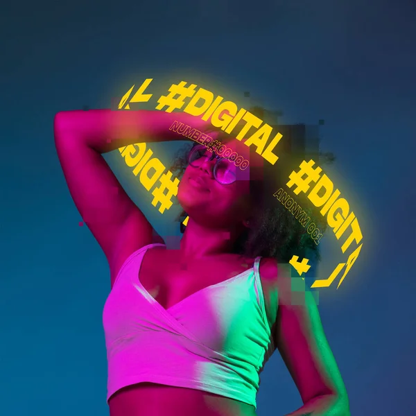 Modern design. Young cheerful woman with neon lettering around head isolated over dark blue background with pink neon light — Stock Photo, Image