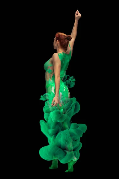Retrato de jovem mulher emotiva coberto com tinta verde e pintura respingo posando, dançando isolado sobre fundo preto. Visão traseira — Fotografia de Stock